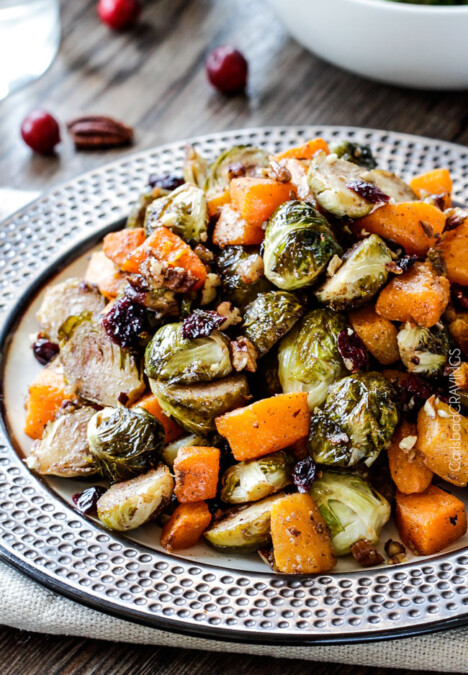 Easy Roasted Brussel Sprouts and Butternut Squash roasted in Dijon Maple Butter Sauce and tossed with cranberries and bacon for the BEST combo ever! tangy, salty, sweet, crunchy, crispy!
