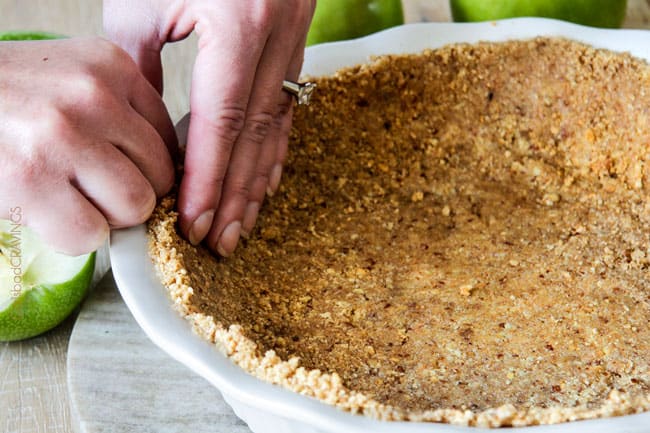 edges of a no bake graham cracker crust with pecans being crimped