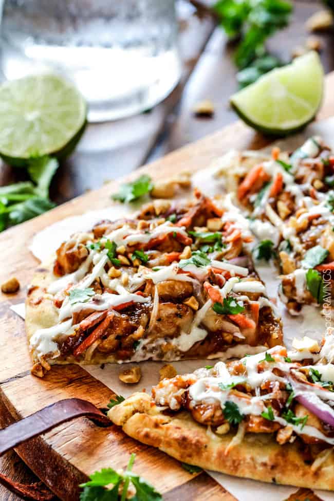 CPK inspired 25 Minute Thai Chicken Flatbread Pizza smothered in easy tangy peanut sauce, tender chicken, mozzarella cheese, crunchy carrots, sprouts and peanuts and the option of creamy coconut yogurt drizzle - an amazing flavor bursting quick dinner at a fraction of the cost. up close of a slice of Thai Chicken Pizza recipe