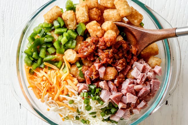 Easy, hearty Breakfast Enchiladas stuffed with your favorite breakfast ingredients then smothered with intoxicatingly delicious Creamy Salsa Sauce! These enchiladas are totally customizable, perfect for your leftover holiday ham AND you can assemble the night before and bake the next day! showing how to make breakfast enchiladas by adding tater tots, ham, bell peppers, cheese, salsa to a glass bowl