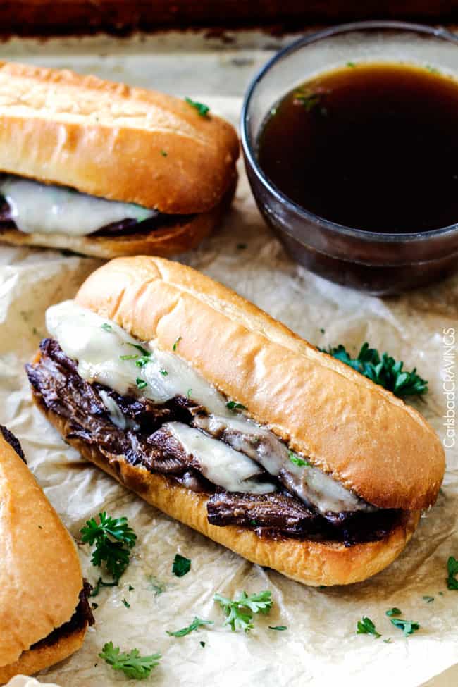 5 minute prep Crazy tender Slow Cooker French Dip Sandwiches seeping with spices are unbelievably delicious and make the easiest dinner or party food. You haven't had French Dip Sandwiches until you try these! Slow Cooker French Dip Sandwiches with dipping sauce on the side.