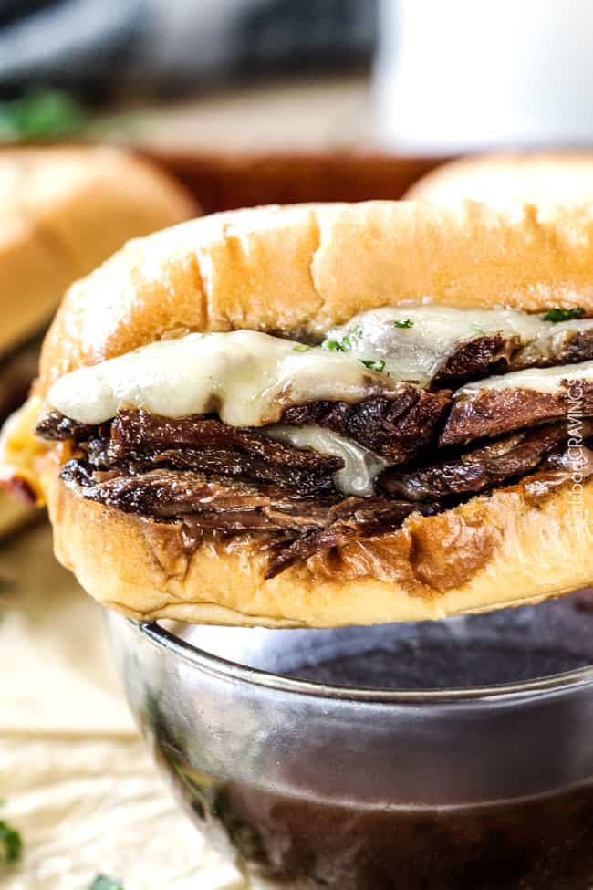 5 minute prep Crazy tender Slow Cooker French Dip Sandwiches seeping with spices are unbelievably delicious and make the easiest dinner or party food. You haven't had French Dip Sandwiches until you try these! Side view of Slow Cooker French Dip Sandwiches showing cheese and meat.
