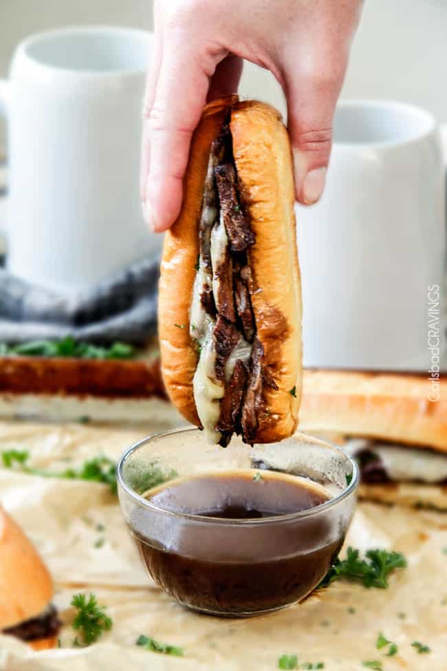 5 minute prep Crazy tender Slow Cooker French Dip Sandwiches seeping with spices are unbelievably delicious and make the easiest dinner or party food. You haven't had French Dip Sandwiches until you try these! Crock pot French Dip Sandwich being dipped in and dripping with au jus