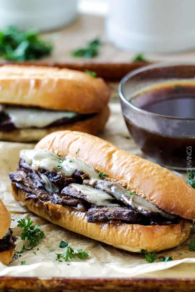 5 minute prep Crazy tender Slow Cooker French Dip Sandwiches seeping with spices are unbelievably delicious and make the easiest dinner or party food. You haven't had French Dip Sandwiches until you try these! Aide view of Slow Cooker French Dip Sandwiches with dipping sauce.