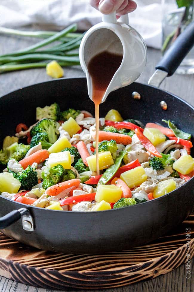 showing how to make Chicken Egg Rolls by pouring sauce into vegetables