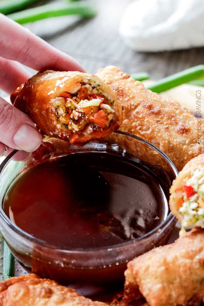 Sweet and Sour Chicken Egg are the best egg rolls I’ve ever had with the best sweet and sour sauce! And made extra fast with the food processor. I am bringing these to all my holiday parties! #appetizer #NewYears #Christmas dipping a chicken egg roll in sweet and sour sauce