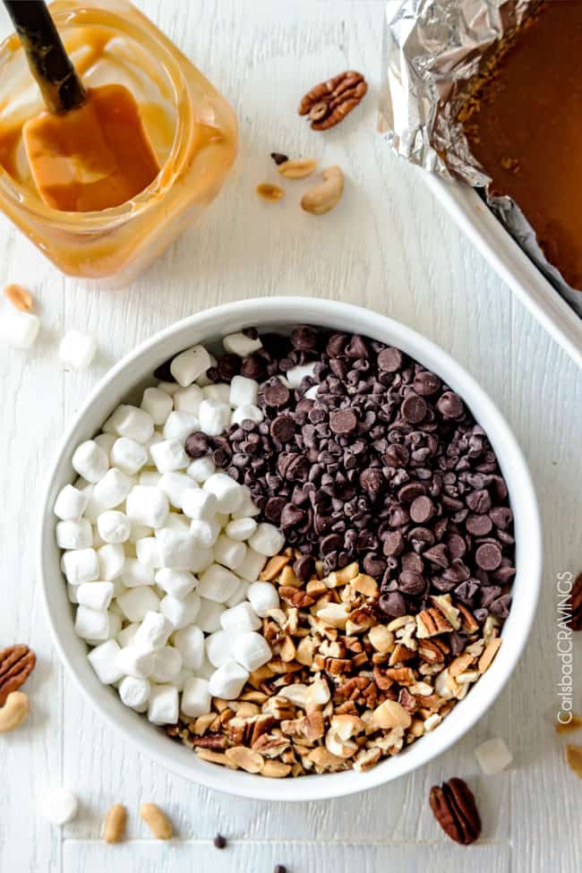 Showing how to make Caramel Nut S'mores Bars mixing ingredients in a white bowl.