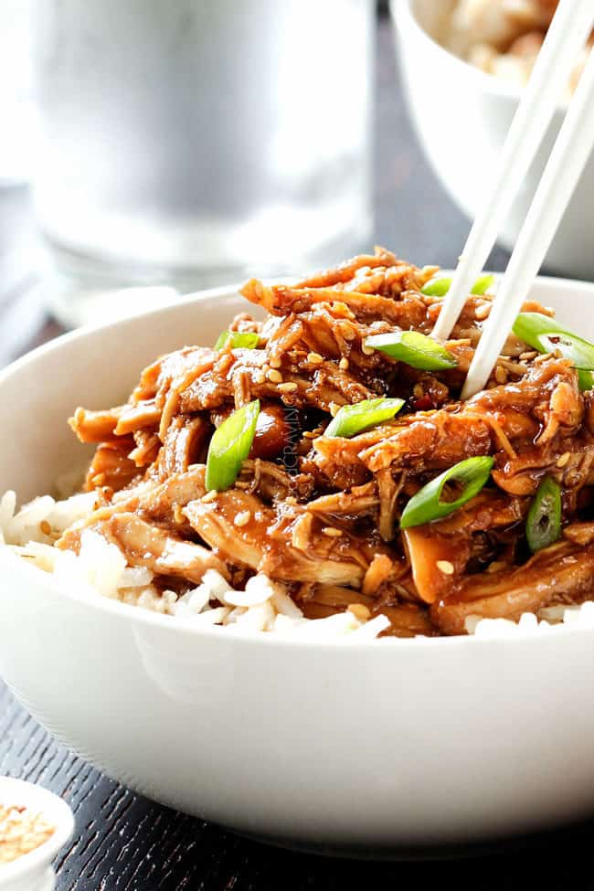 Slow Cooker Honey Soy Chicken is one of our family favorites with the most incredible sauce! Super easy and way better than takeout! up close of chopsticks picking up honey soy chicken breasts