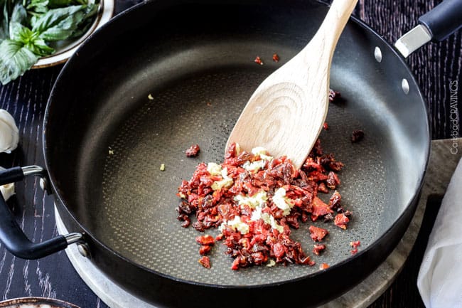 Showing how to make Sun-dried Tomato Fettuccine Alfredo by cooing sun dried tomatoes with garlic.