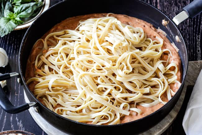 Adding pasta to the Sun-dried Tomato Alfredo Sauce.