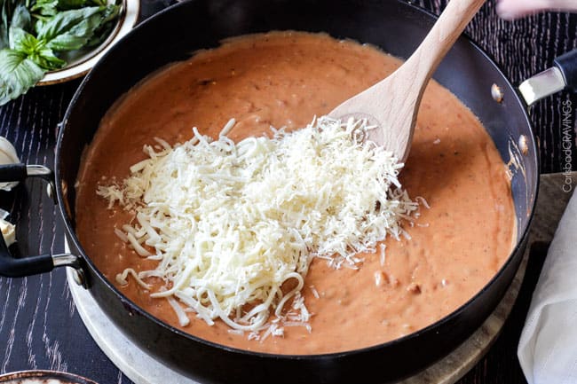 Showing how to make Sun-dried Tomato Fettuccine Alfredo by adding cheese to the sauce.