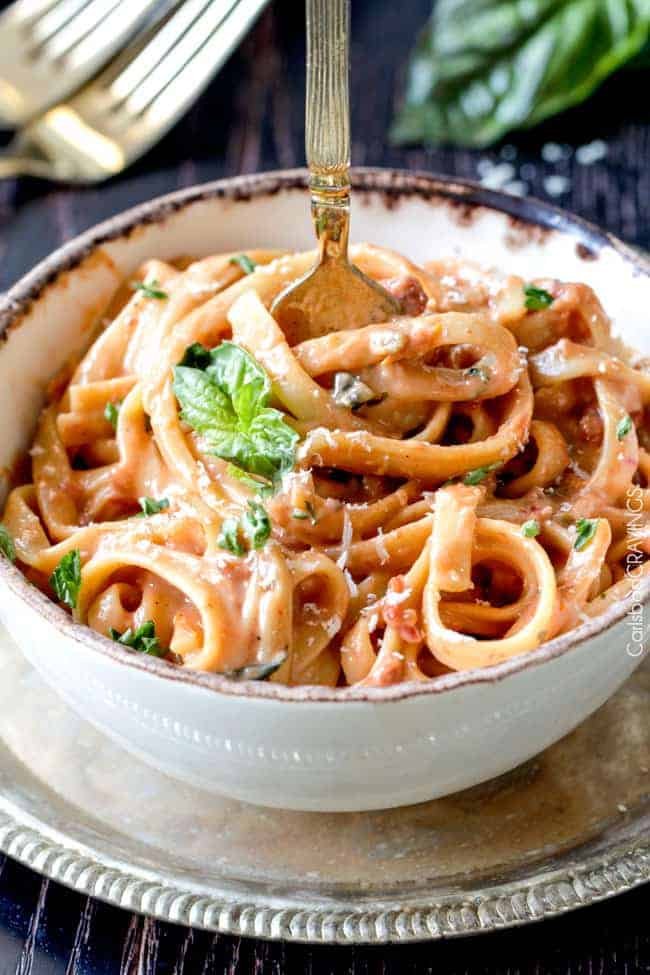 Close up of a bowl of Sun-dried Tomato Fettuccine Alfredo with basil on top.