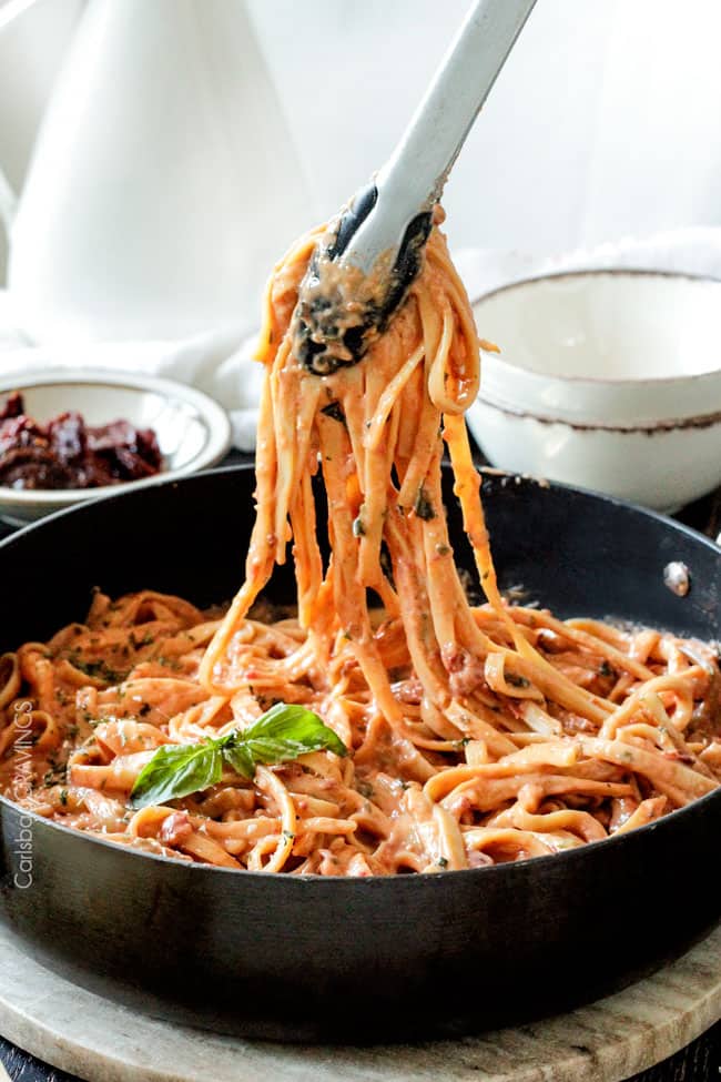 Showing A bowl of Sun-dried Tomato Fettuccine Alfredo being served from a pan.