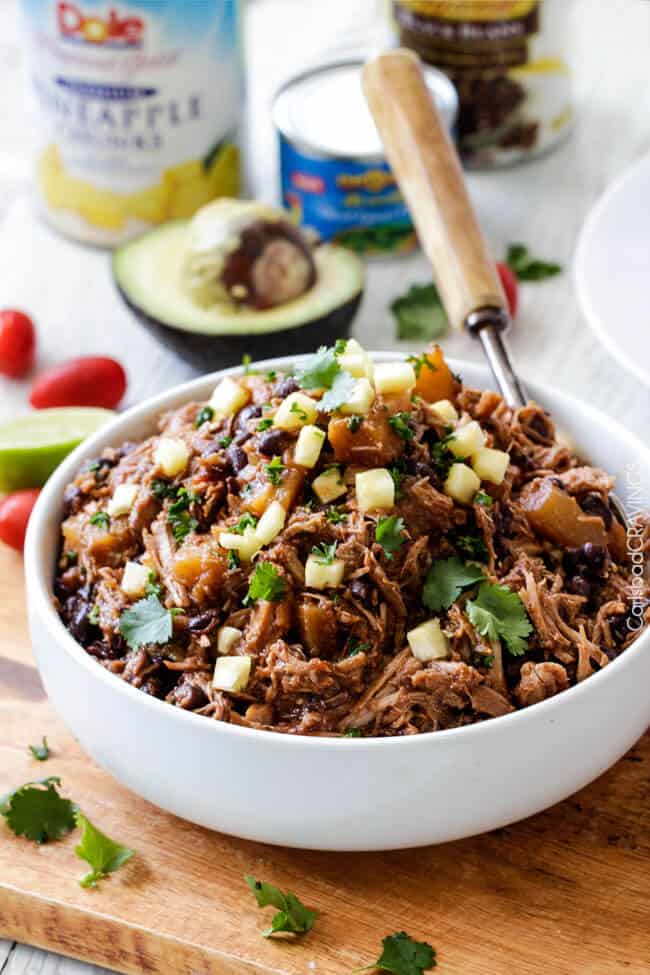 Slow Cooker Pineapple Salsa Pork n a white bowl with a spoon and avocado near the plate.