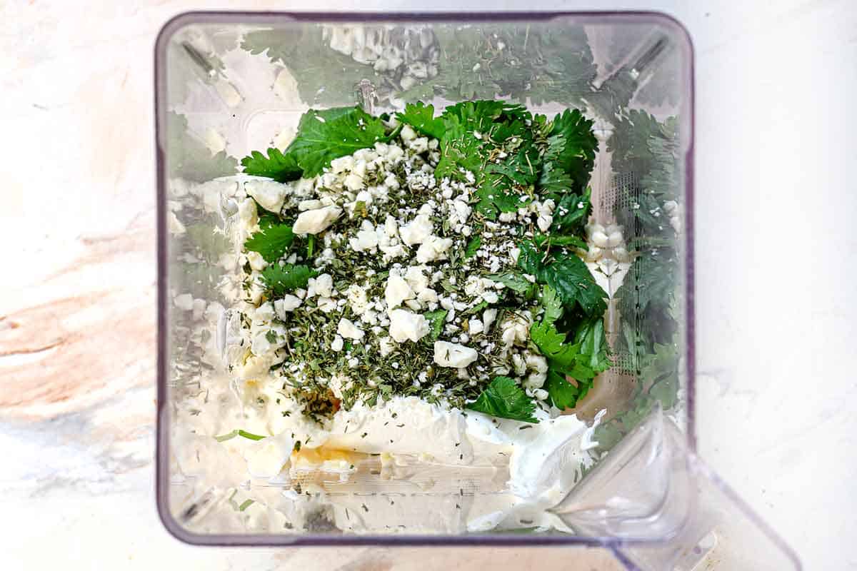 showing how to make buffalo chicken tacos by adding the blue cheese cilantro ranch ingredients to the blender and blending until smooth