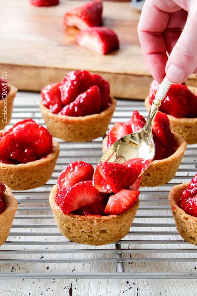 Showing how to make Mini Strawberry Pies with Sugar Cookie Crust by adding strawberries.