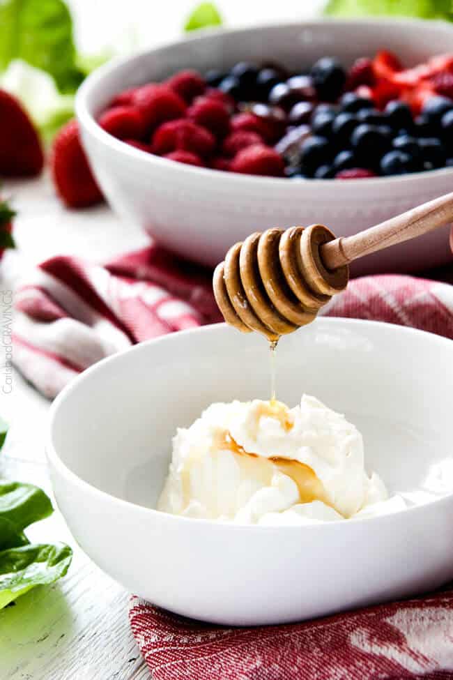 Showing how to make Berry Salad by making Honey and Mascarpone in a white bowl.