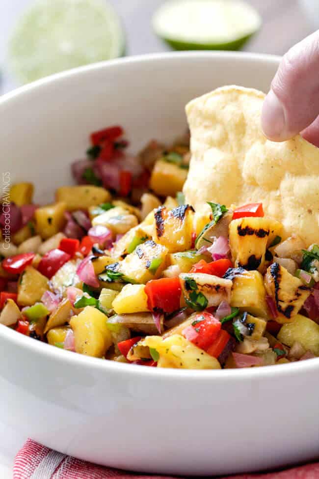 Close up view of Grilled Pineapple Pear Salsa eating with a corn chip.
