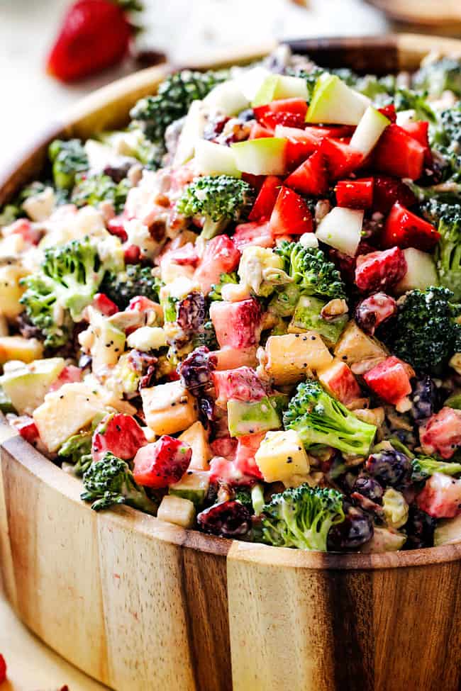 Best Broccoli Salad tossed in creamy dressing in a wood bowl with avocados and stawberries