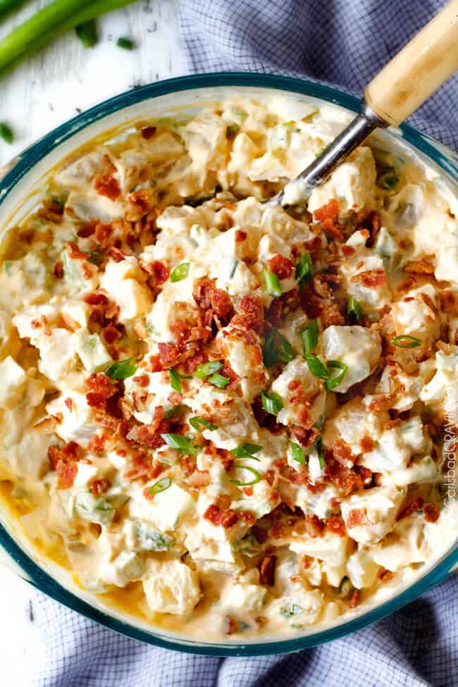 Everyone needs the best potato salad recipe and this is it! so creamy and flavorful and disappears in minutes whenever I take it any where - everyone always asks for the recipe!! top view of a glass bowl of homemade potato salad with a serving spoon