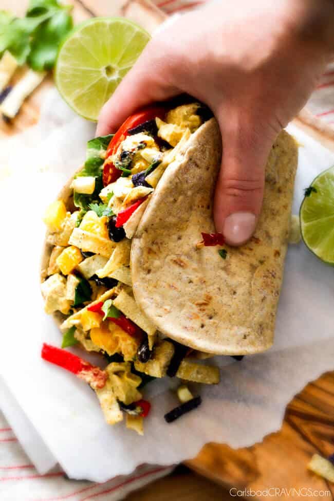 These Avocado Chicken Salad Sandwiches are my favorite way to use leftover chicken! They are super easy, creamy, flavorful, refreshing and I love the Mexican spices and crunch of tortilla strips! a hand picking up an Avocado Chicken Salad Sandwich
