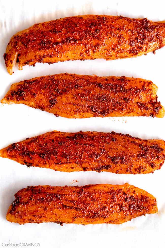 Mind blowing Blackened Tilapia Fish Tacos with a quick marinade and the most flavorful spice rub! These are hands down the BEST FISH TACOS ever! And the sweet and tangy Pineapple Cucumber Slaw and Avocado Crema hit this one out of the park! seriously better than my favorite restaurant! showing how to make Tilapia Fish Tacos by adding a wet spice rub all over the tilapia fillets