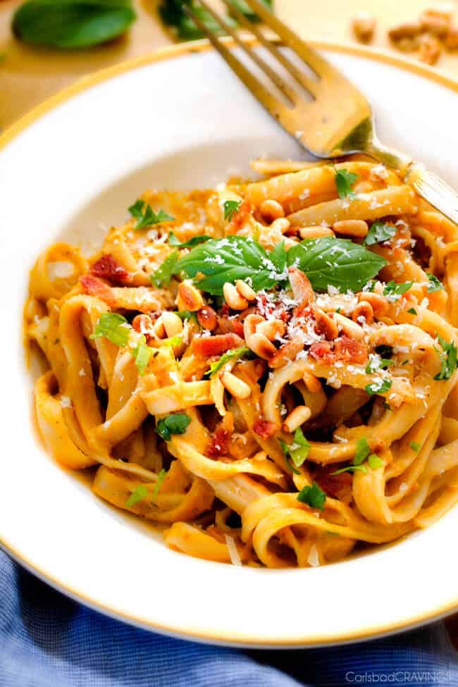 Creamy Butternut Squash Pasta - silky quick and easy pasta that is SO creamy and absolutely addicting! Infused with fresh Parmesan, seasoned to perfection and topped with crispy bacon and toasted pine nuts! #glutenfree #fall a white bowl of butternut squash with bacon