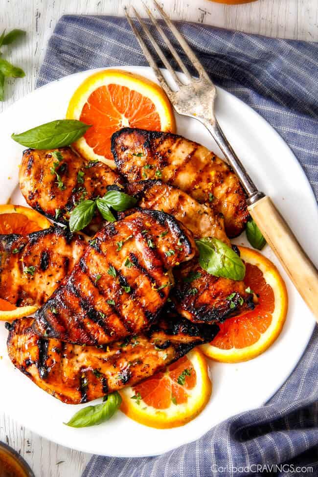 Chipotle Maple Chicken with grill marks on a plate with oranges.