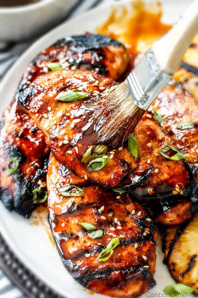 5 Minute prep Easy Teriyaki Chicken infused with Sweet Chili Sauce for added depth of flavor and YUM! The marinade doubles as the sauce for an easy family favorite that tastes better than takeout! My family loves this with rice and stir fried veggies and I love it on salad or in wraps! Teriyaki Chicken breasts being brushed with homemade teriyaki sauce