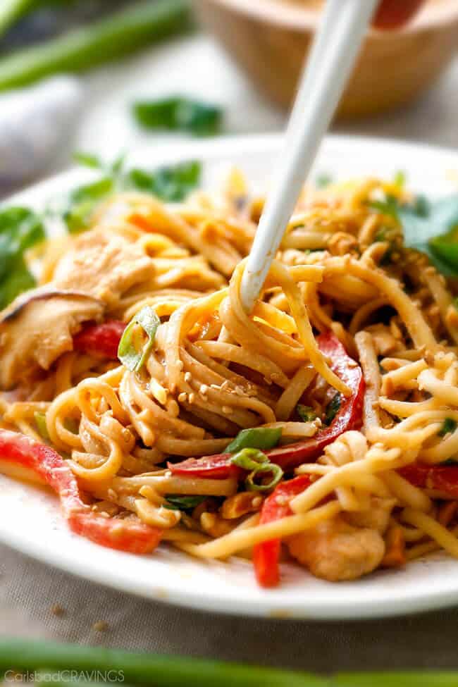 30 Minute Peanut Sesame Noodles (with Chicken and Veggies) - super quick and easy meal all in one with the most amazing creamy peanut sesame sauce you will crave for days! up close of white chopsticks swirling easy sesame noodles on a white plate