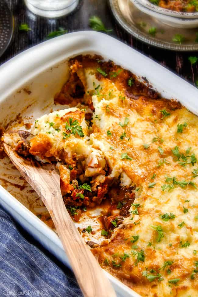 Savory, comforting Boneless Short Rib Shepherd's Pie elevates shepherd's (or cottage pie) to a whole new level with melt in your mouth meat and Swiss Gruyere Mashed Potatoes! This is guaranteed to be a new family favorite!!! a wood spoon in the best Shepherd's Pie casserole dish