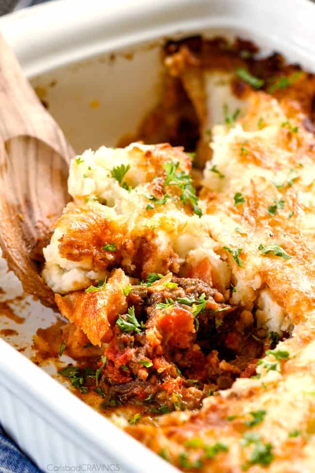 Savory, comforting Boneless Short Rib Shepherd's Pie elevates shepherd's (or cottage pie) to a whole new level with melt in your mouth meat and Swiss Gruyere Mashed Potatoes! This is guaranteed to be a new family favorite!!! scooping out a serving of ultimate Shepherd's Pie from a casserole dish