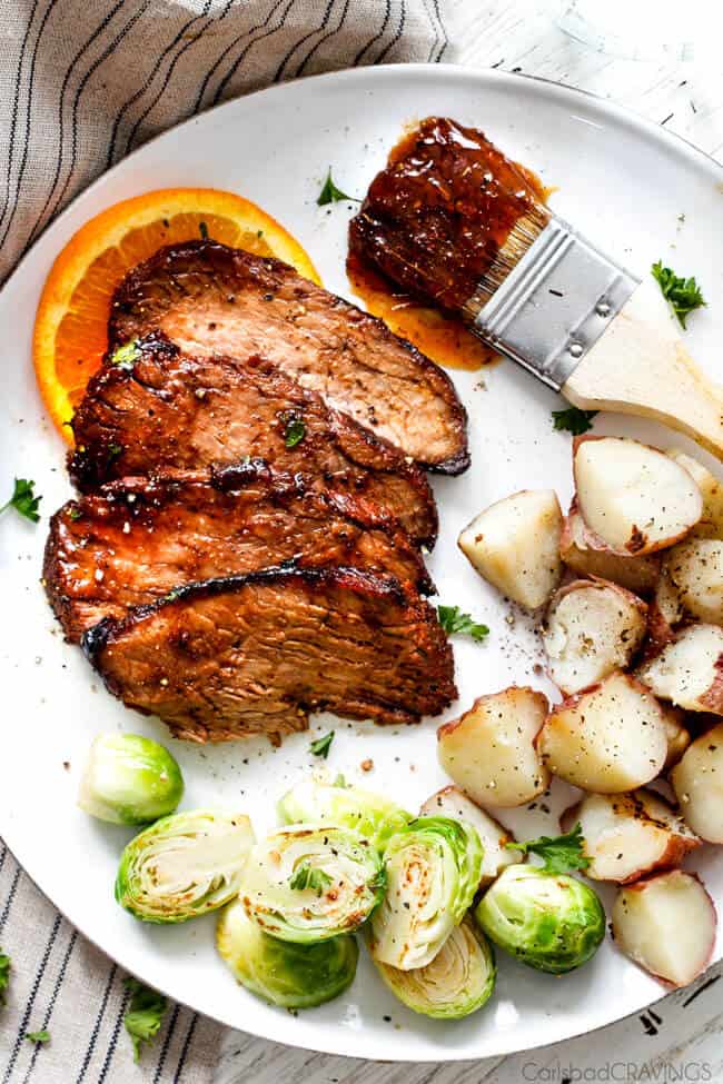 Cajun Steak with Apricot Orange Glaze on a plate with potatoes and brussel sprouts.