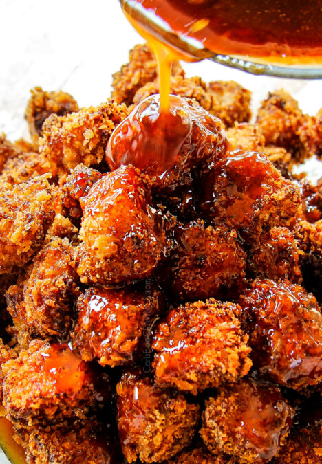 showing how to make Chinese Lemon Chicken by drizzling fried chicken pieces with lemon sauce