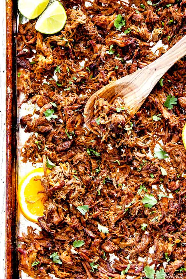 Mexican carnitas meat on sheet pan with wooden spoon showing how to make crispy