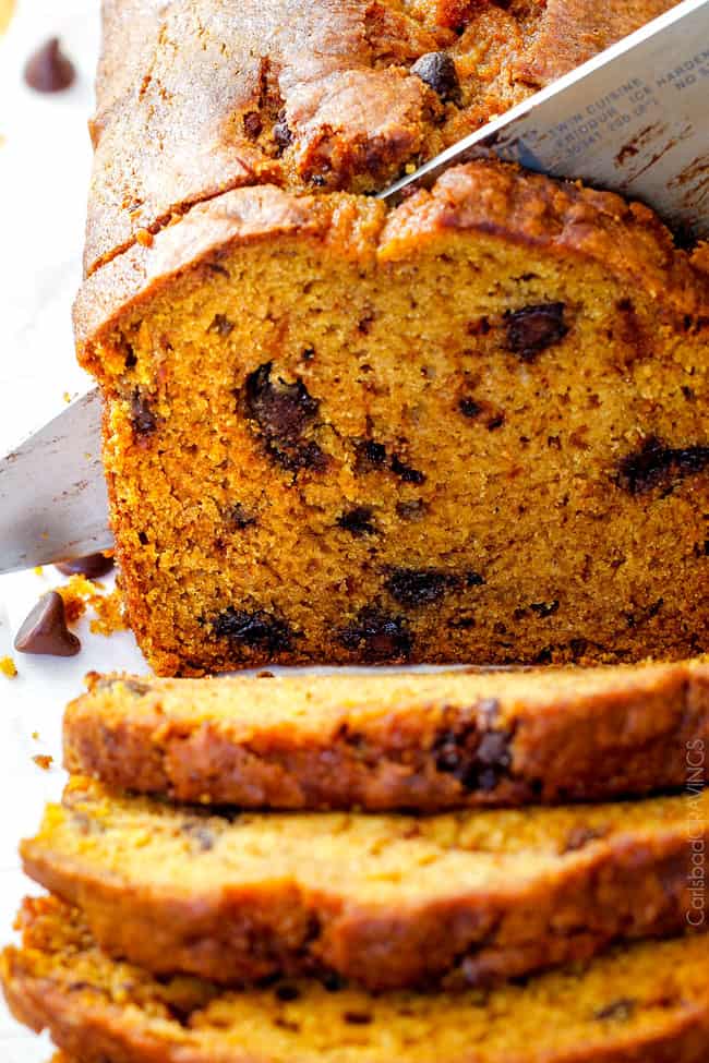 My Mom’s Famous Chocolate Chip Pumpkin Bread! So incredibly moist, infused with cinnamon, cloves and nutmeg with only 2 bowls and one whisk required! Everyone will BEG you for this recipe! up close shot of slicing easy pumpkin bread