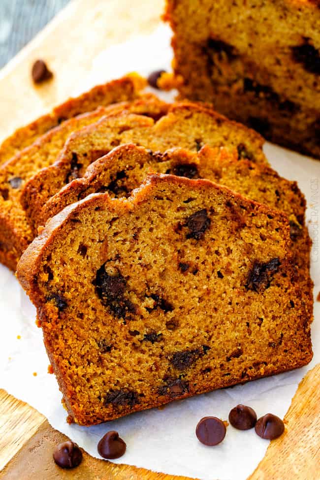 My Mom’s Famous Chocolate Chip Pumpkin Bread! So incredibly moist, infused with cinnamon, cloves and nutmeg with only 2 bowls and one whisk required! Everyone will BEG you for this recipe! slices of the best pumpkin bread recipe on a cutting board