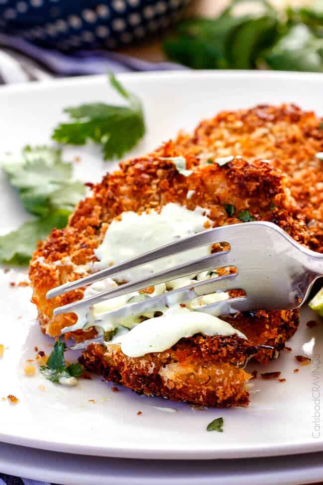 Easy, extra crispy, restaurant quality Crab Cakes right in your own home! Crispy on the outside, moist, juicy, flavor packed on the inside with the BEST DIP ever!! You can also make ahead of time for stress free appetizers! a fork taking a bite of a crispy crab cake smothered in crab cake sauce