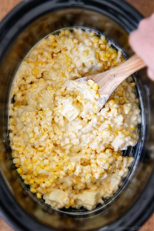 Slow Cooker Creamed Corn with Ricotta and Bacon - this has to be the BEST CREAMED CORN I've eaten in my entire life! Rich and creamy, seasoned to perfection, SO easy and practically fool proof! Definitely making this every Thanksgiving from now on! showing how to make best creamed corn by stirring corn with butter and cream cheese in slow cooker.