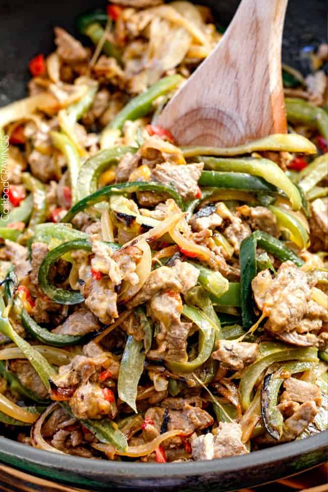 these crazy tender, flavorful Philly Cheesesteak Sandwiches are the BEST EVER! The incredible marinated steak and spiced mayo set these worlds above other recipes I've tried. You seriously haven't tried Philly Cheesesteak Sandwiches until you try these - and so much easier than you think! showing how to make easy philly cheese steak recipe with an up close view of cheese melting with steak and bell peppers in the skillet