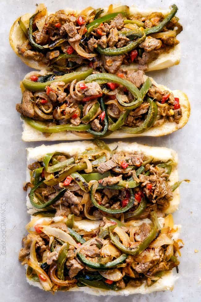 these crazy tender, flavorful Philly Cheesesteak Sandwiches are the BEST EVER! The incredible marinated steak and spiced mayo set these worlds above other recipes I've tried. You seriously haven't tried Philly Cheesesteak Sandwiches until you try these - and so much easier than you think! showing how to make Philly Cheesesteak Sandwich recipe by adding the steak, bell peppers and cheese filling on hoagie buns