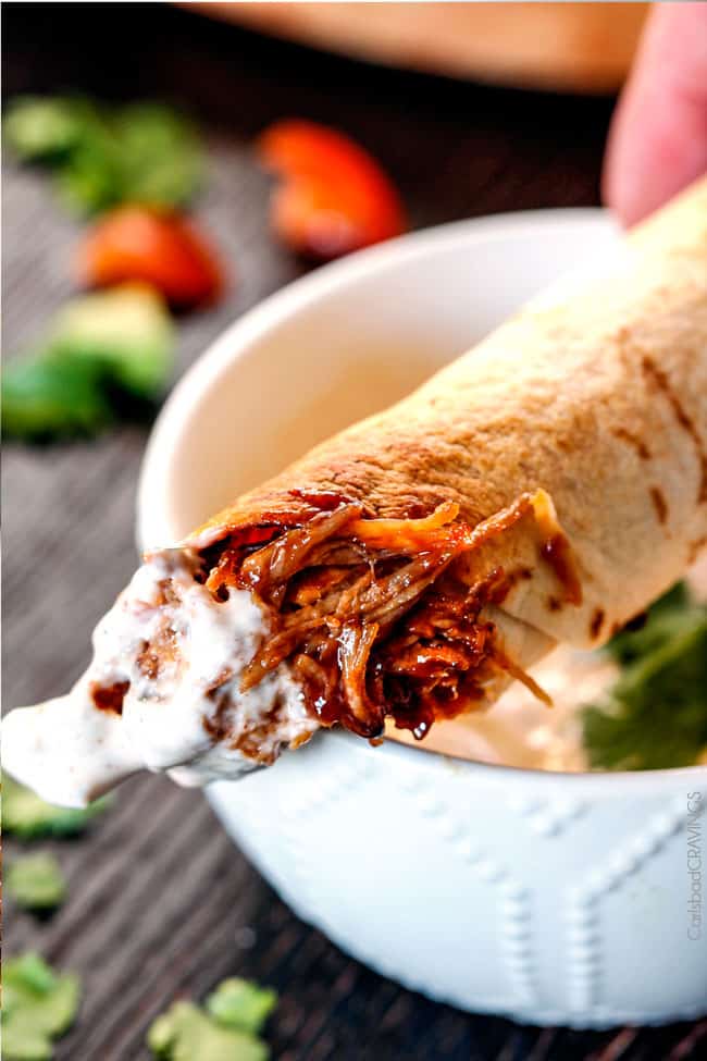 BBQ Pork Taquitos dipped in sauce with a bite.