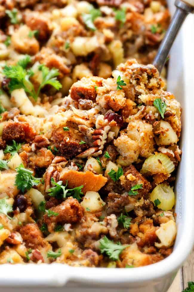 Thanksgiving Cornbread Sausage Stuffing (Dressing) with dried cranberries, apples and pecans is is destined to become your new go-to recipe!! The wonderfully savory, buttery herb infused stuffing is moist, flavorful, easy and absolutely addicting! up close of cornbread stuffing with sausage, apples, pecans, craisins