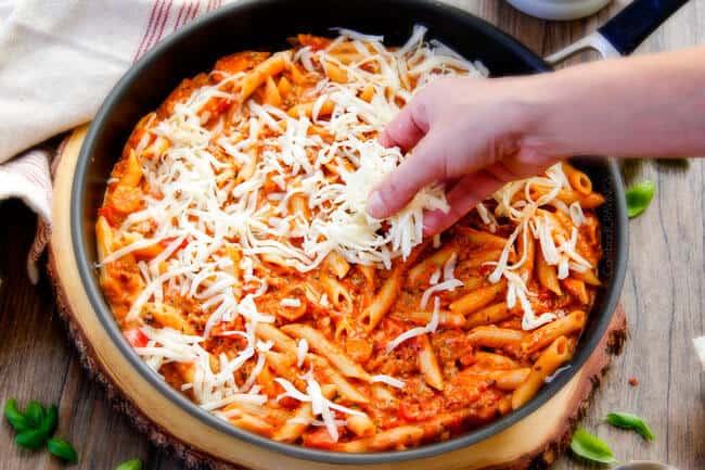 Adding cheese to Cheesy Penne & New York Bakery® Bake Garlic Bread.