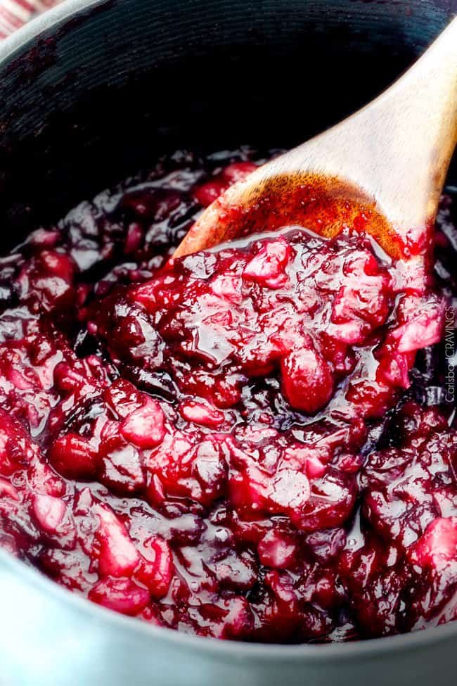 Pineapple Cranberry Sauce mixing with a wood spoon.