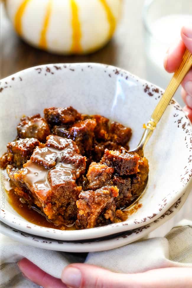 a bowl of pumpkin bread pudding being eaten with a spoon