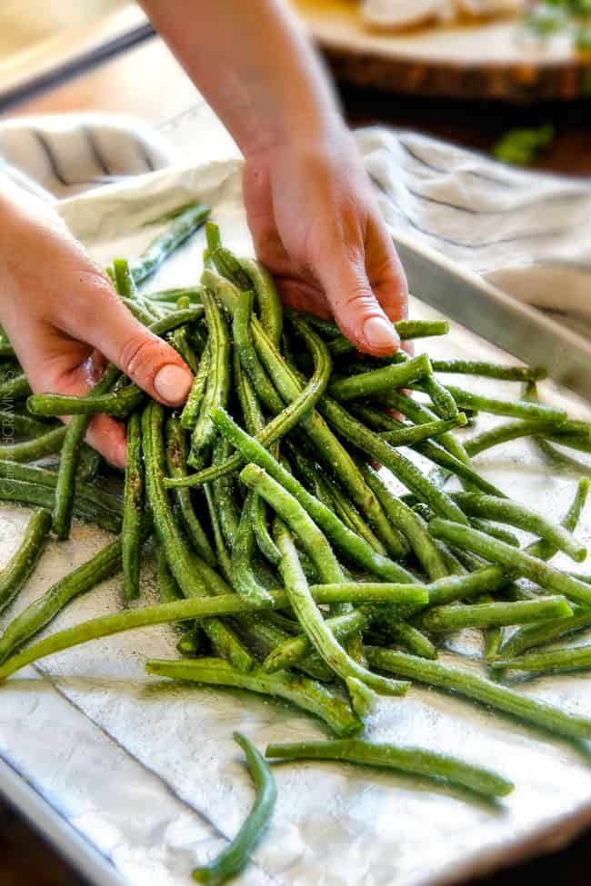 Roasted Green Beans with Cremini Bacon Mushroom Sauce - these beans are amazing! wonderfully flavorful, crisp tender and the silky Cremini Bacon Mushroom Sauce is out of this world! If you are looking for an alternative to green bean casserole, this is it! #thanksgiving Showing how to make Roasted Green Beans with Bacon by tossing green beans with olive oil salt and pepper on a baking sheet
