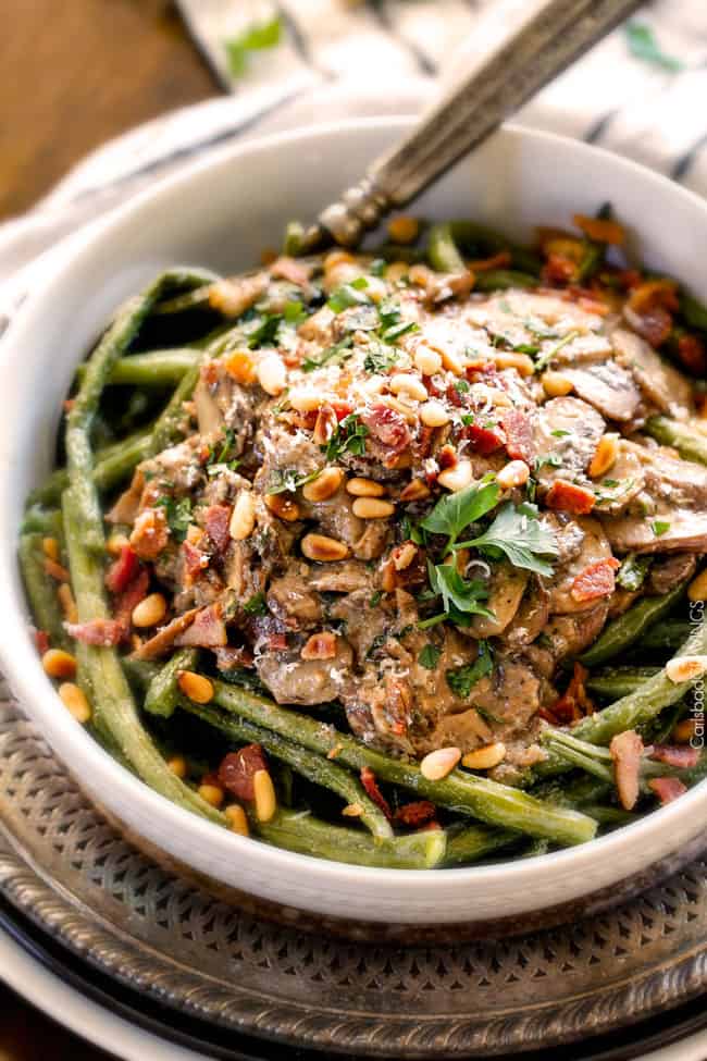 Roasted Green Beans with Cremini Bacon Mushroom Sauce - these beans are amazing! wonderfully flavorful, crisp tender and the silky Cremini Bacon Mushroom Sauce is out of this world! If you are looking for an alternative to green bean casserole, this is it! #thanksgiving up close of a big white bowl of Roasted Green Beans with Bacon