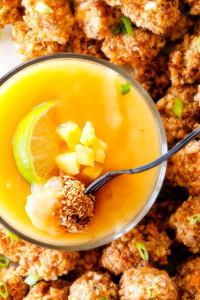 Baked Coconut Cashew Chicken Bites being dipped in sauce.