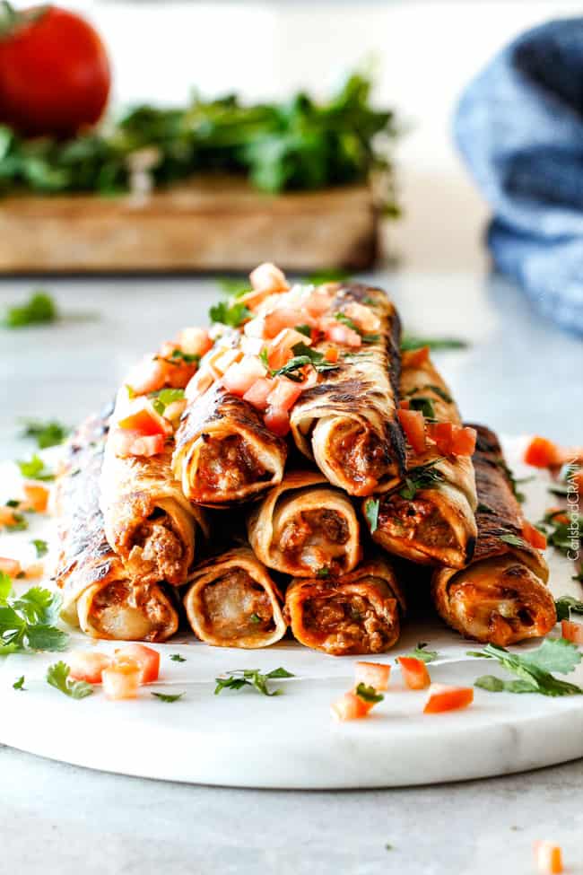 Cooked Jalapeno Popper Beef Taquitos with tomatoes and cilantro.